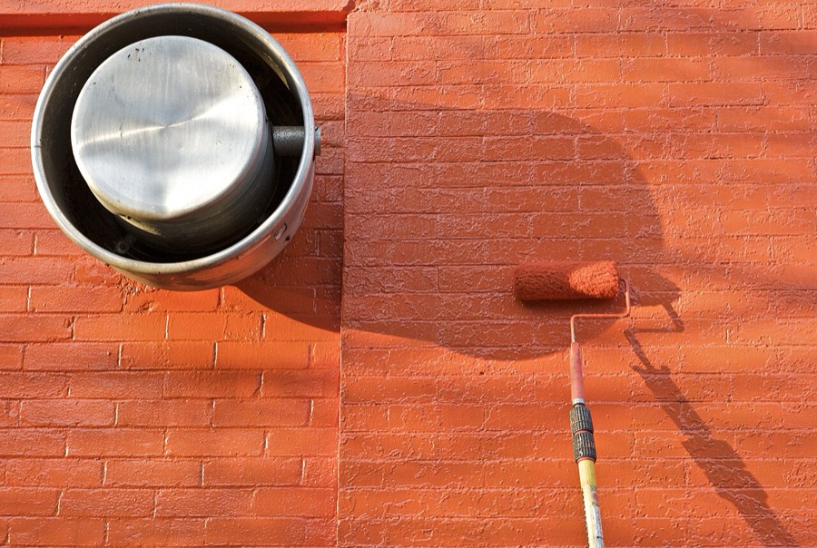 Paint roller and metal drum against a freshly painted wall